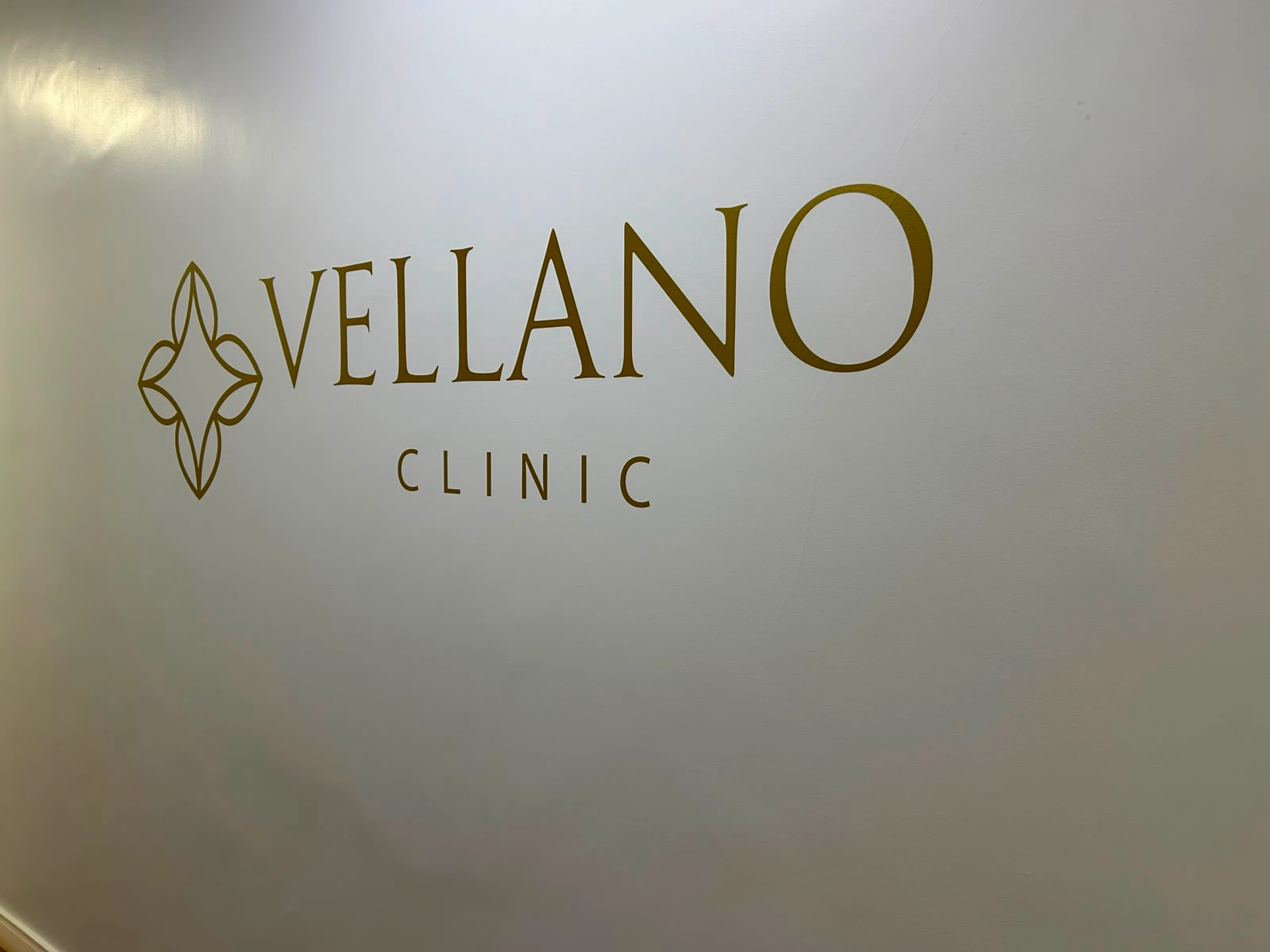 Parede com logo dourada da Vellano Clinic