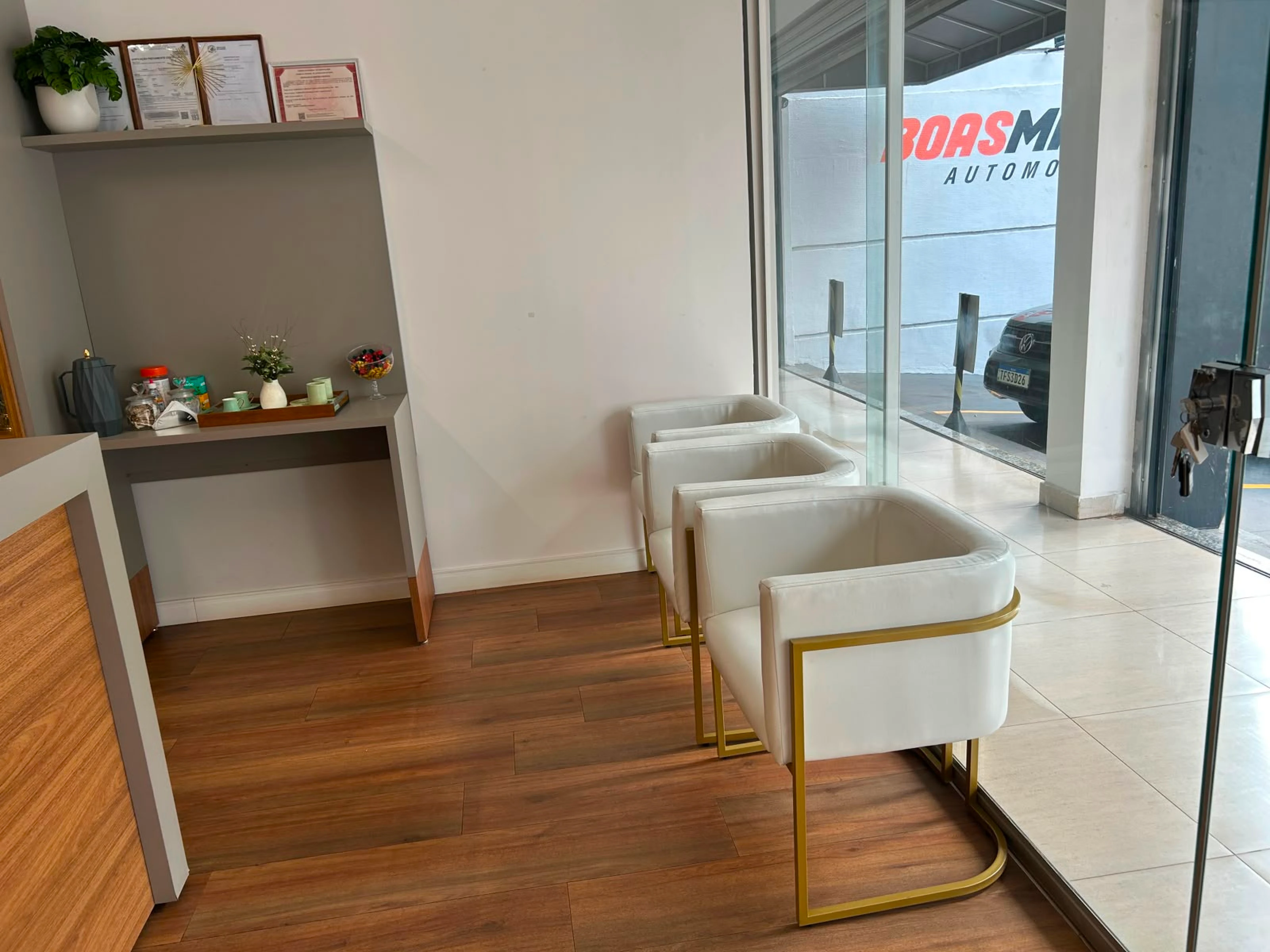 Sala de espera da Vellano Clinic com poltronas brancas e douradas e entrada envidraçada