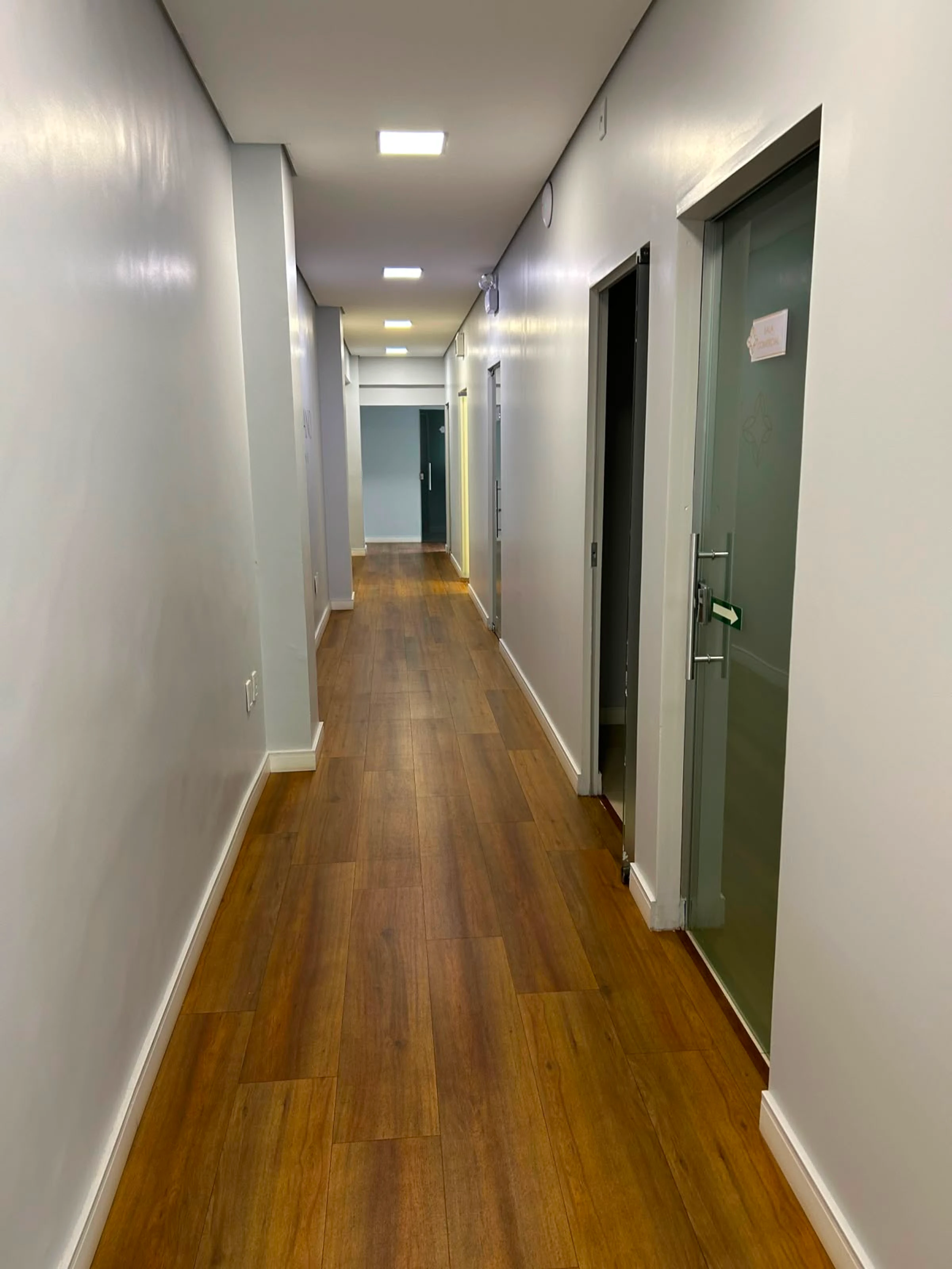 Corredor da Vellano Clinic com piso de madeira e acesso às salas de atendimento
