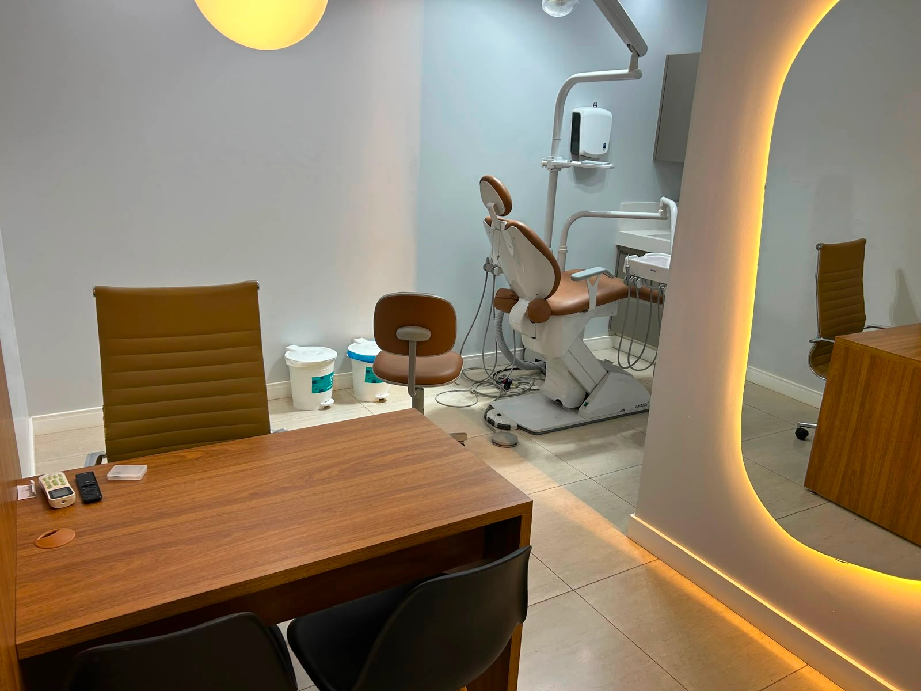 Sala odontológica com cadeira de tratamento e espelho com iluminação dourada