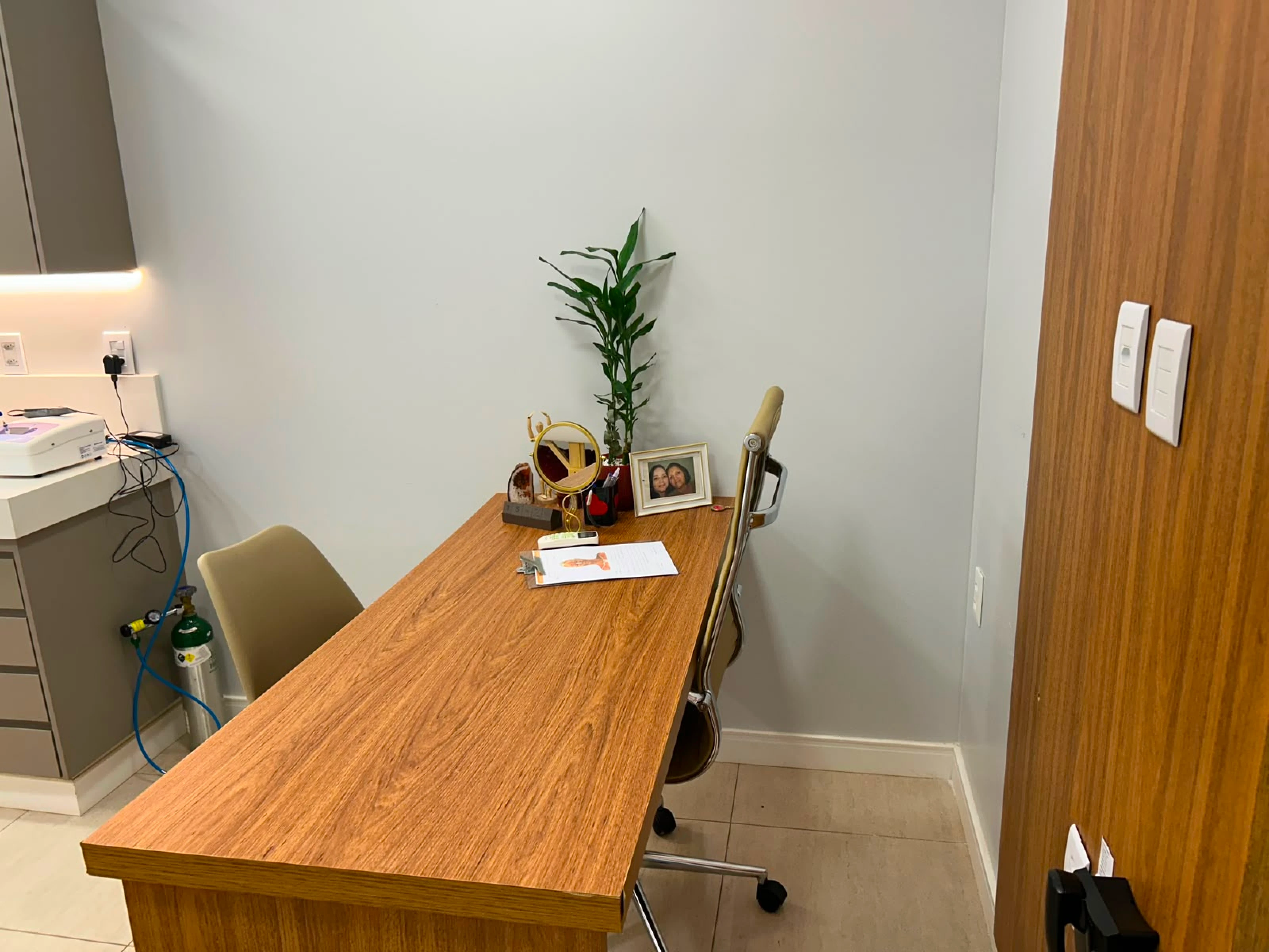 Sala de consulta com mesa de atendimento e bancada de equipamentos