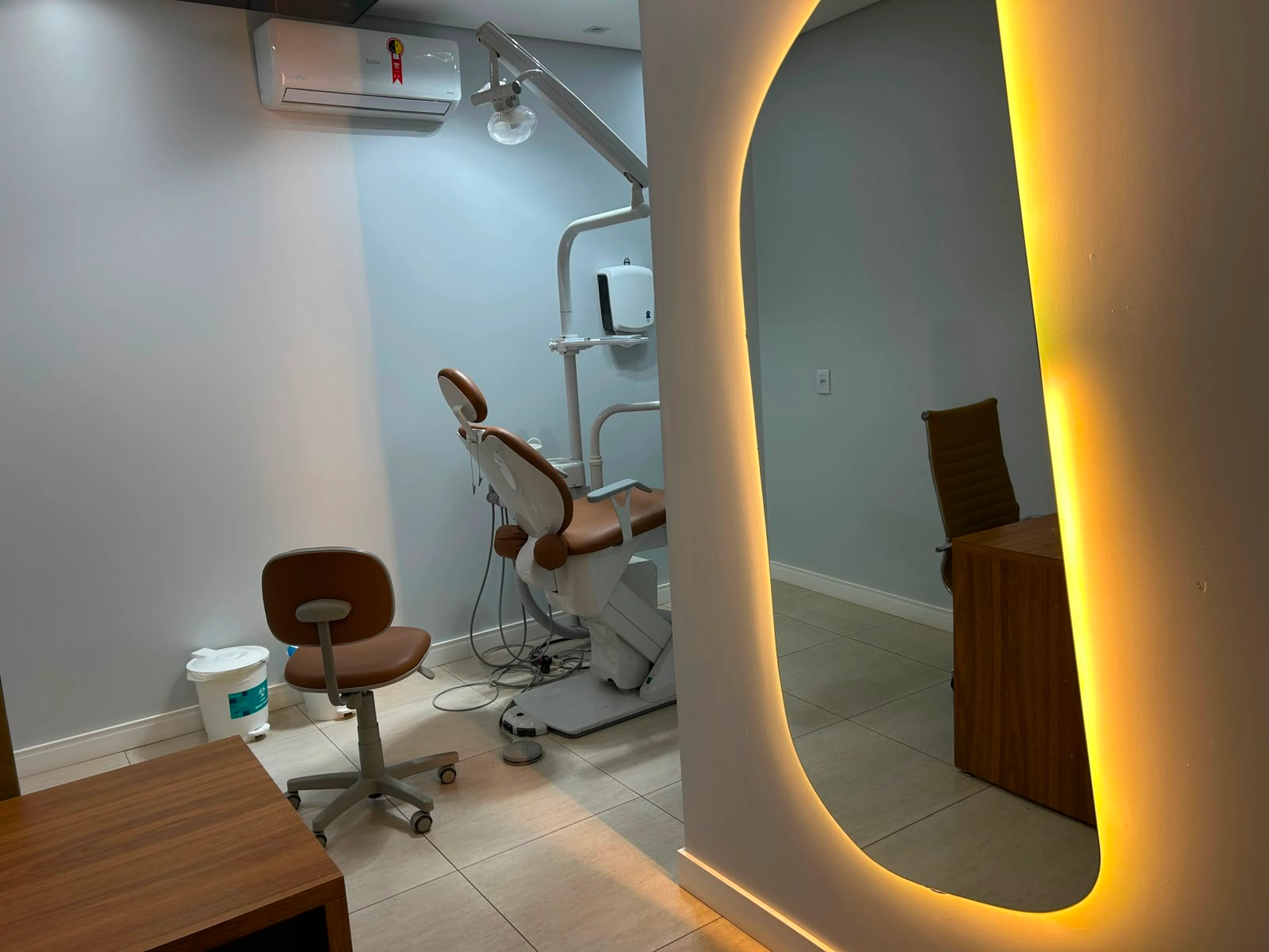 Sala odontológica com cadeira de tratamento e espelho com luz dourada